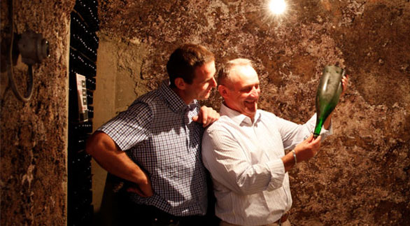 Photo in the cellar with father and son Bandock looking at a bottle of Champagne in the light