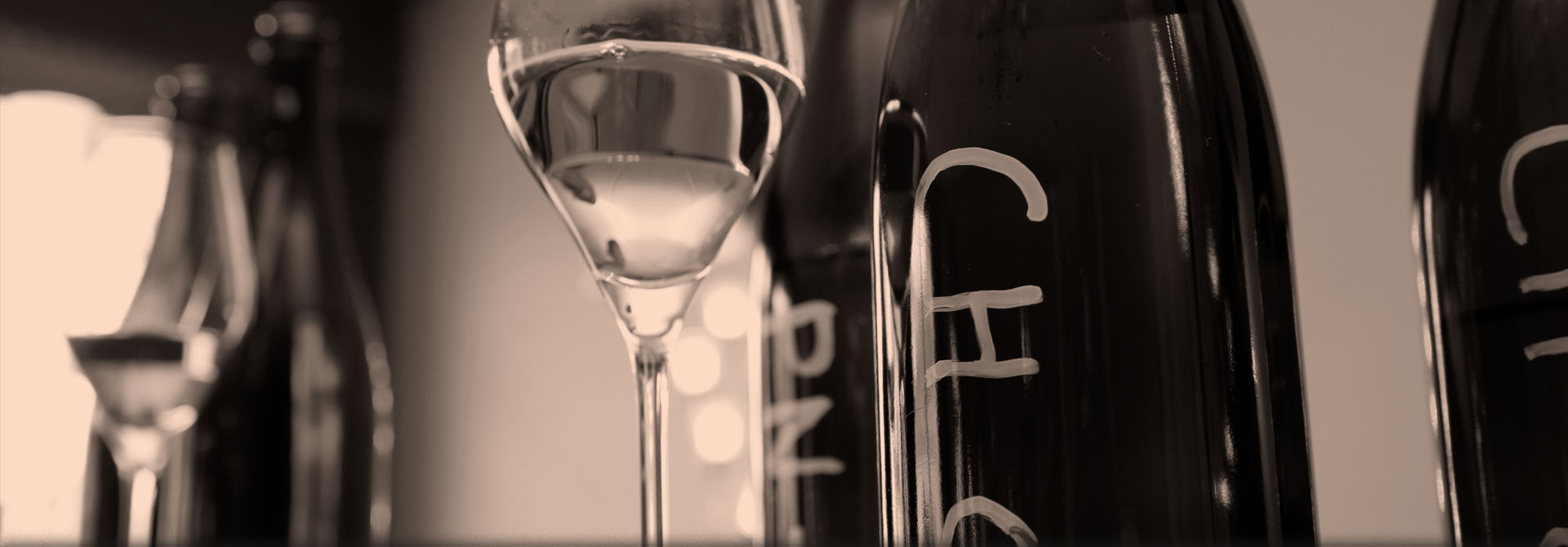 Sepia and blurred artistic photo of a glass bottle and a glass of Champagne