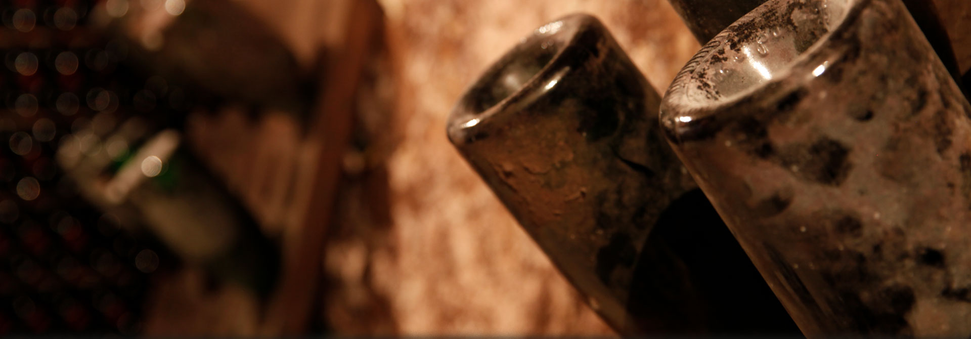 Close-up of bottles of Champagne resting on wooden desks in the cellar